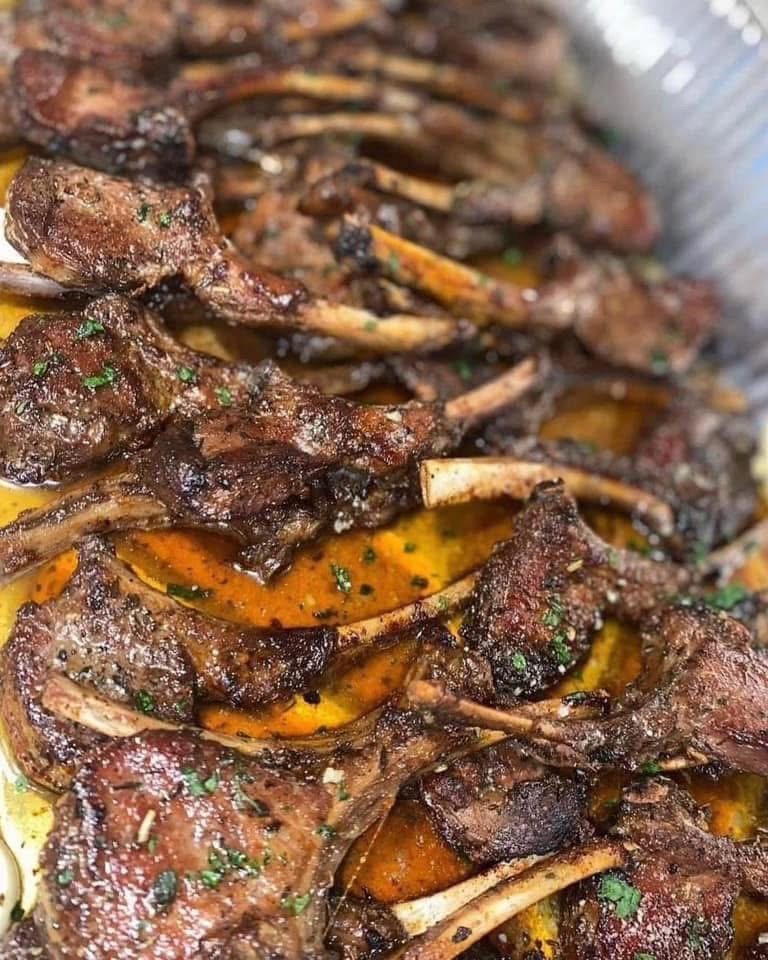 Seasoned lamb chops arranged over sauce