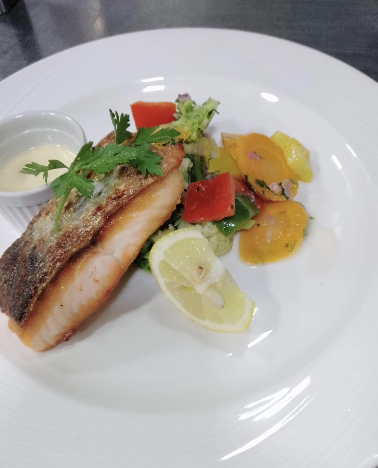 Seared salmon with vegetables and lemon on a white plate