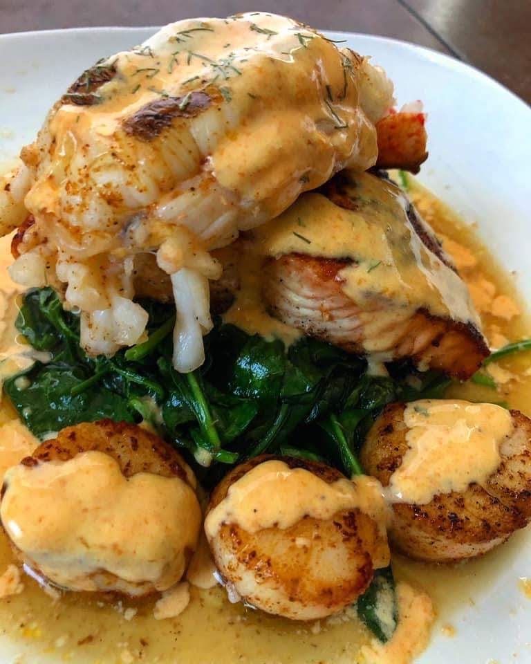 Plated seafood with seared scallops, greens and sauce