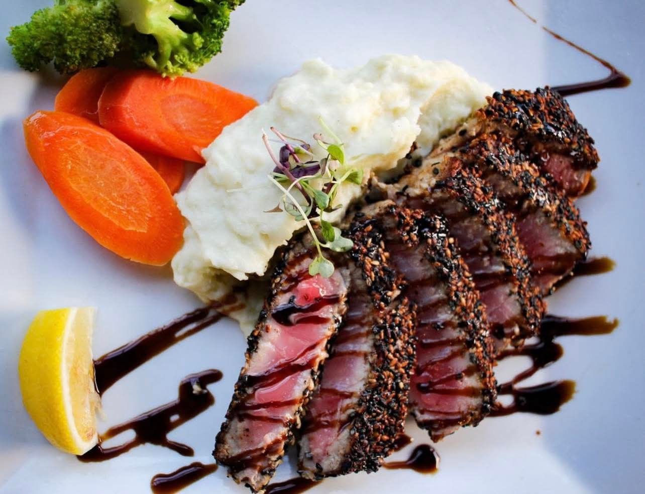 Sliced seared fish with vegetables and mashed potatoes