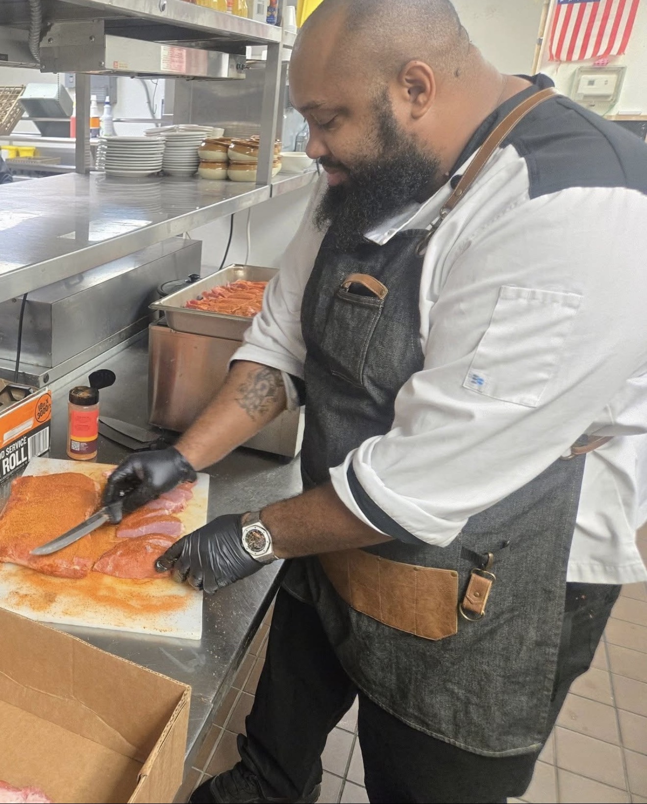 Travis Griffin preparing and seasoning meat in the kitchen